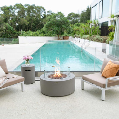 Modeno Tramore Fire Table with wndscreen and flame near on the pool